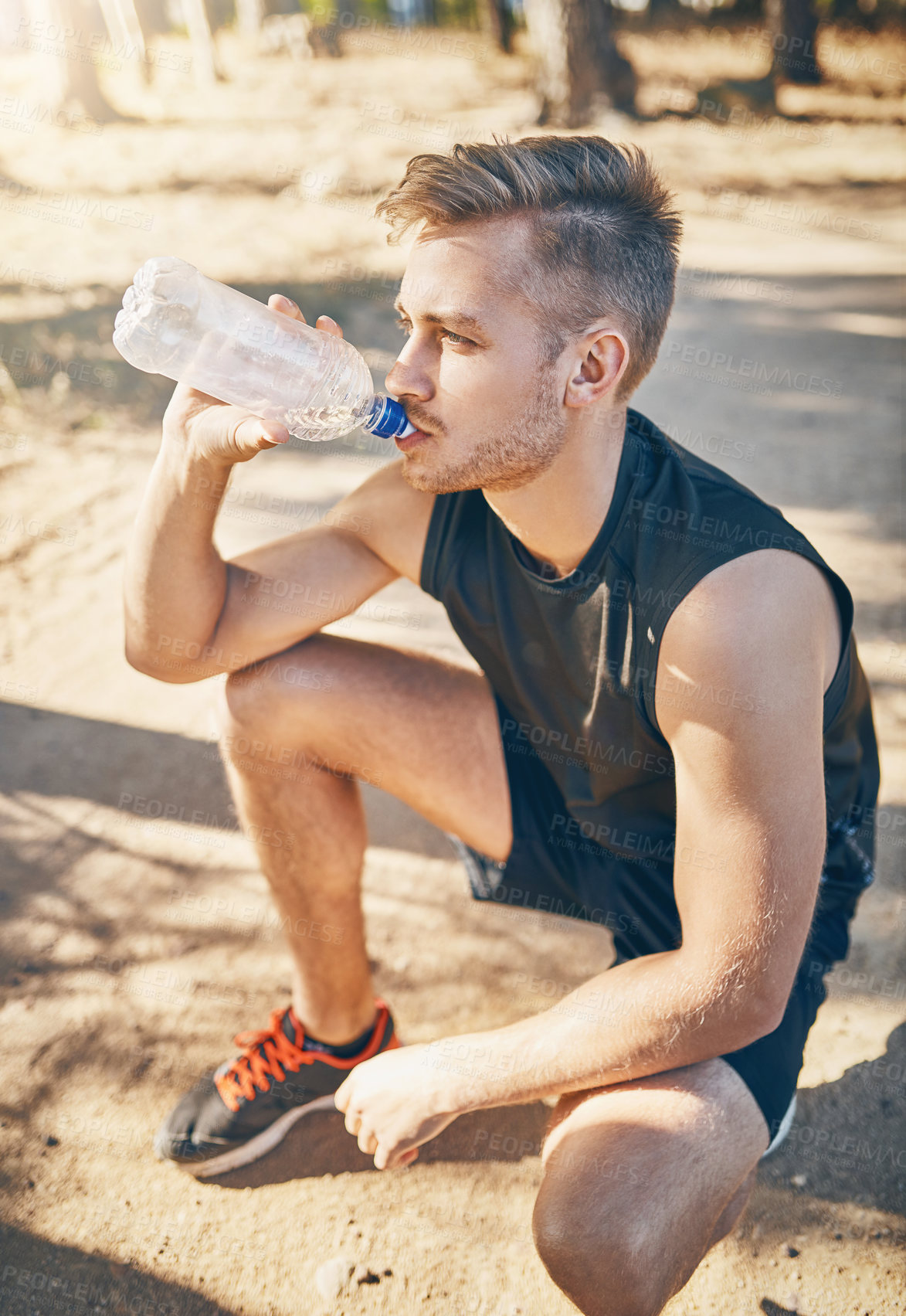 Buy stock photo Shot of a young man drinking water while out for a workout