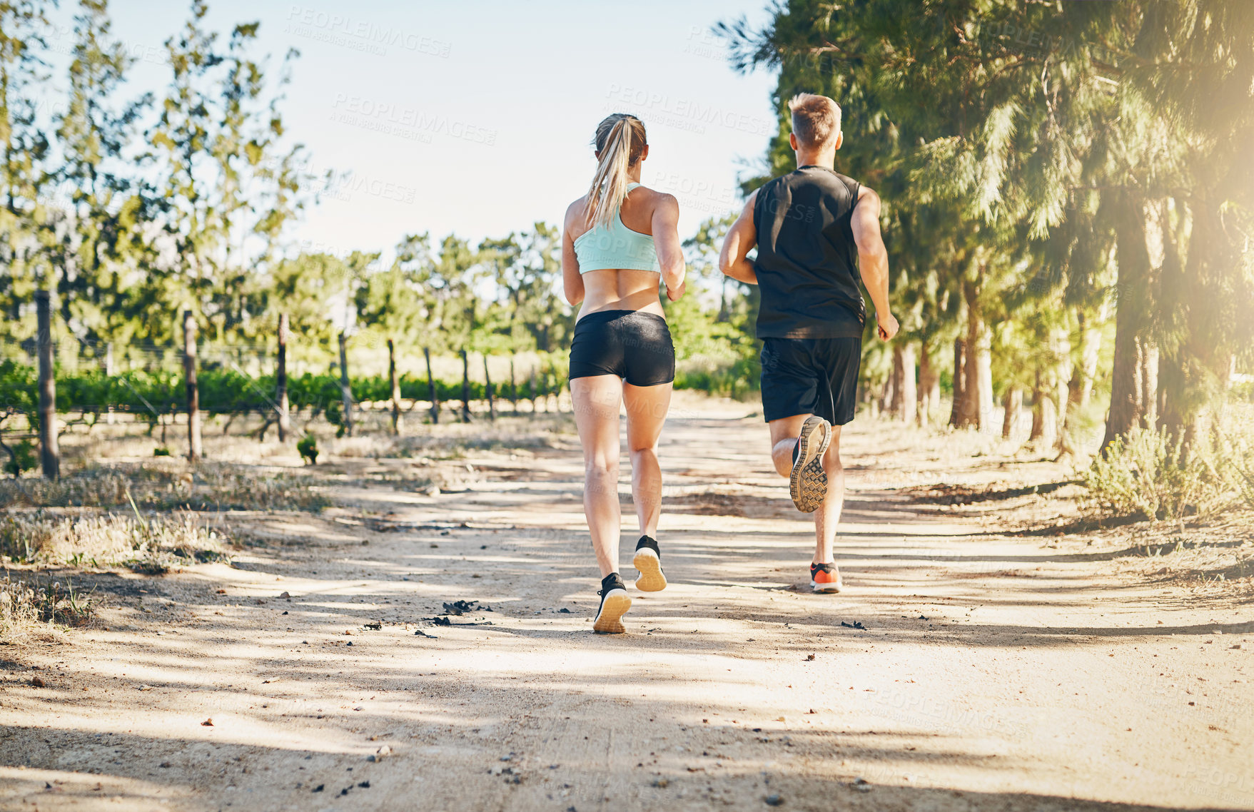 Buy stock photo Rearview shot of a young couple running together outdoors
