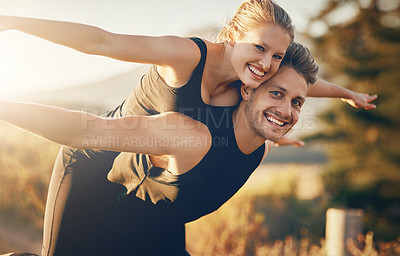 Buy stock photo Shot of a young woman being piggybacked by her boyfriend while they stretch out their arms outdoors