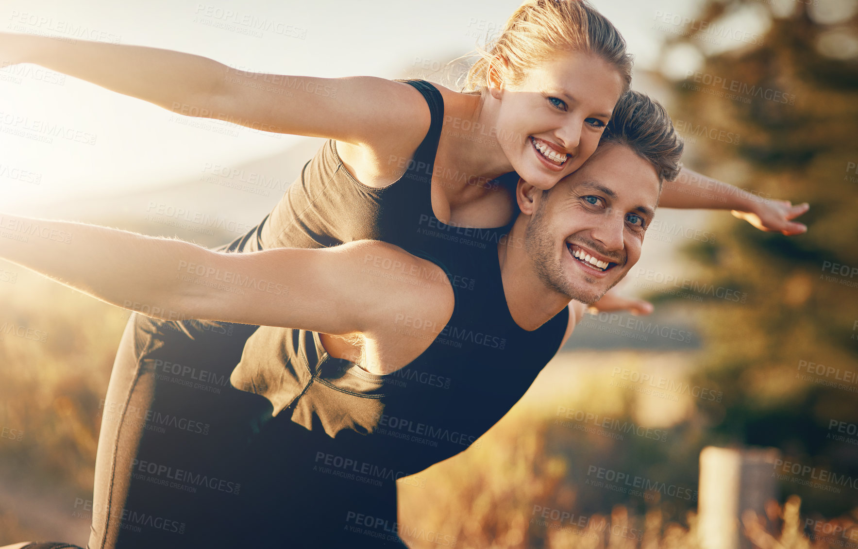 Buy stock photo Shot of a young woman being piggybacked by her boyfriend while they stretch out their arms outdoors