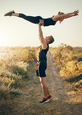 Buy stock photo Shot of a young man lifting his girlfriend above him outdoors