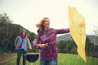 Buy stock photo Man, woman and bbq in rain with umbrella, laugh or surprise weather with climate change in garden. Couple, outdoor and funny fail in storm, backyard or cooking in winter with run, wind or hurricane