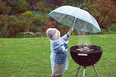 Buy stock photo Weather, nature and boy with a grill, rain and wellness with safety, cover and winter outfit. Bbq, male child or kid with umbrella, cold or young person with food, raincoat or outdoor with protection