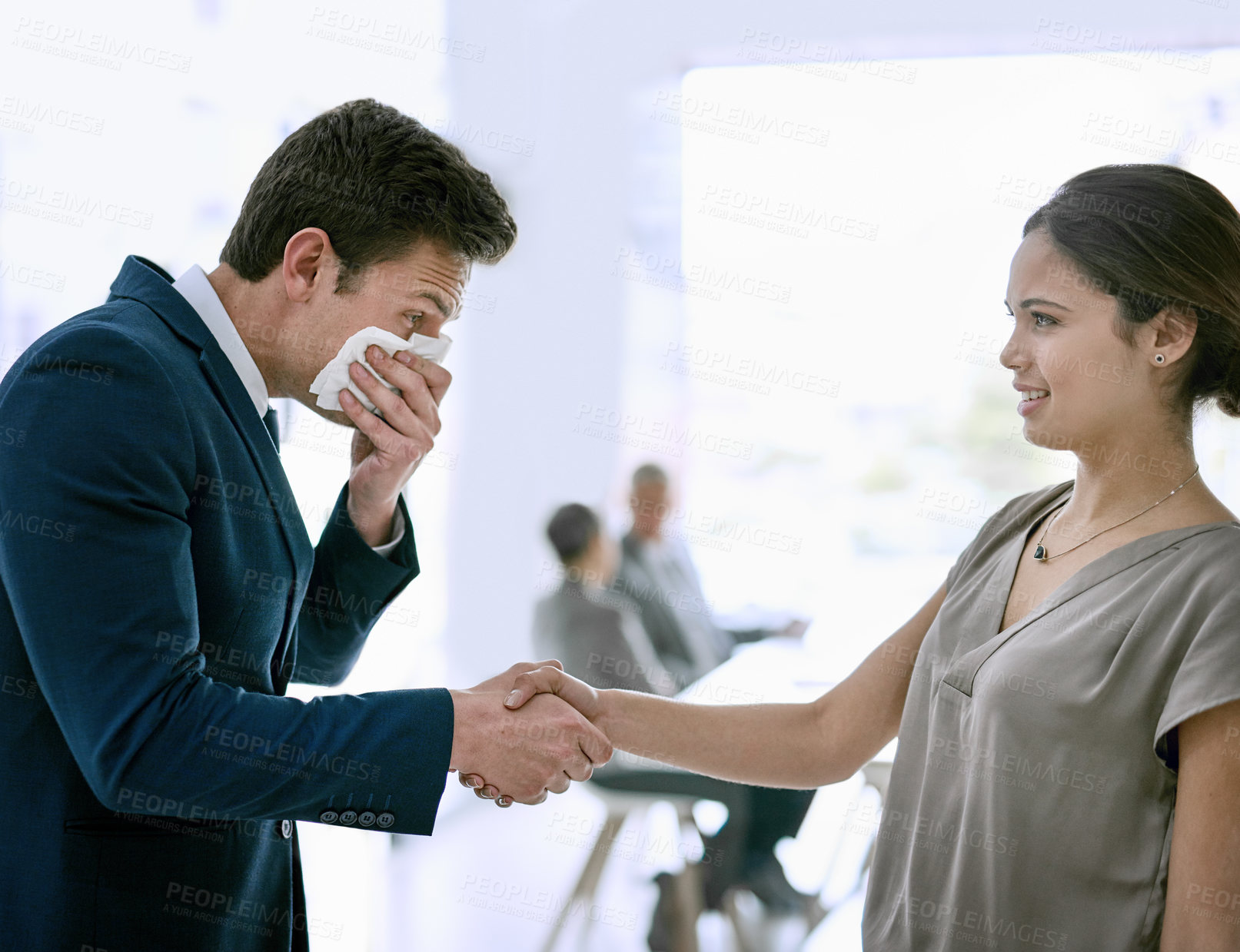 Buy stock photo Cropped shot of a sick businessperson shaking hands with a colleague and sneezing in the office