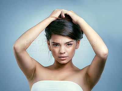Buy stock photo Studio shot of a beautiful young woman with her arms raised holding her hair up  against a blue background