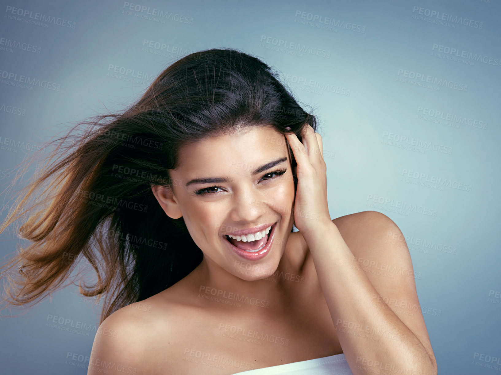 Buy stock photo Studio shot of a beautiful young woman laughing against a blue background