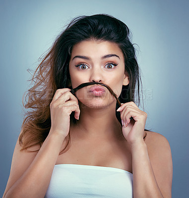 Buy stock photo Studio shot of a beautiful young woman pretending to have a moustache using her hair against a blue background