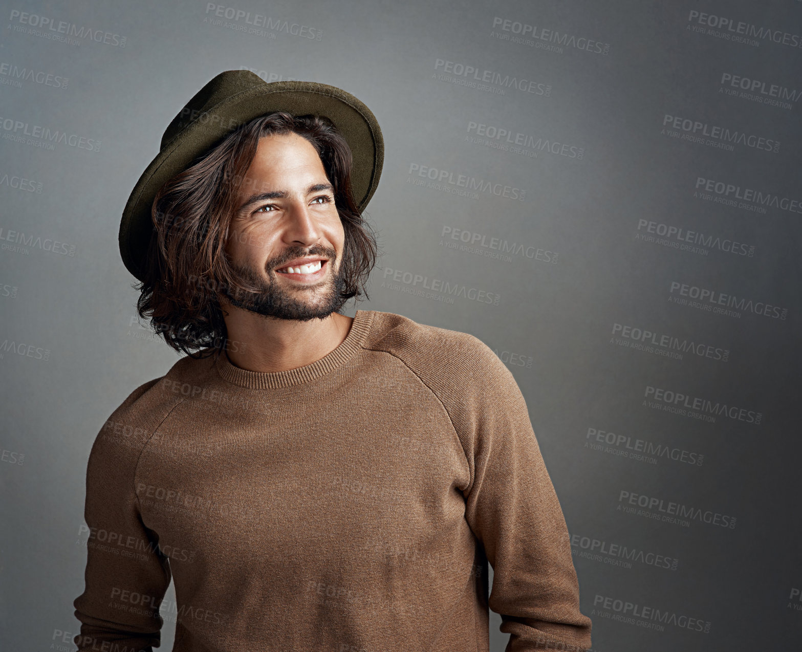 Buy stock photo Studio shot of a happy and handsome young man wearing a hat against a gray background