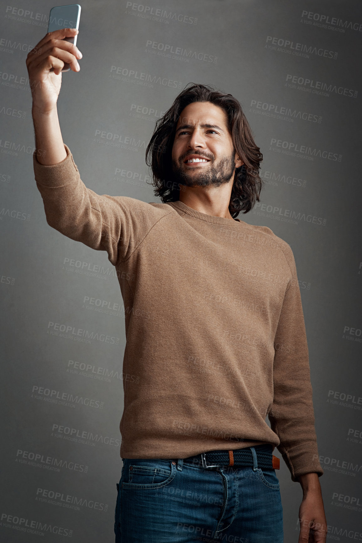 Buy stock photo Studio shot of a handsome young man taking a selfie on his cellphone against a gray background