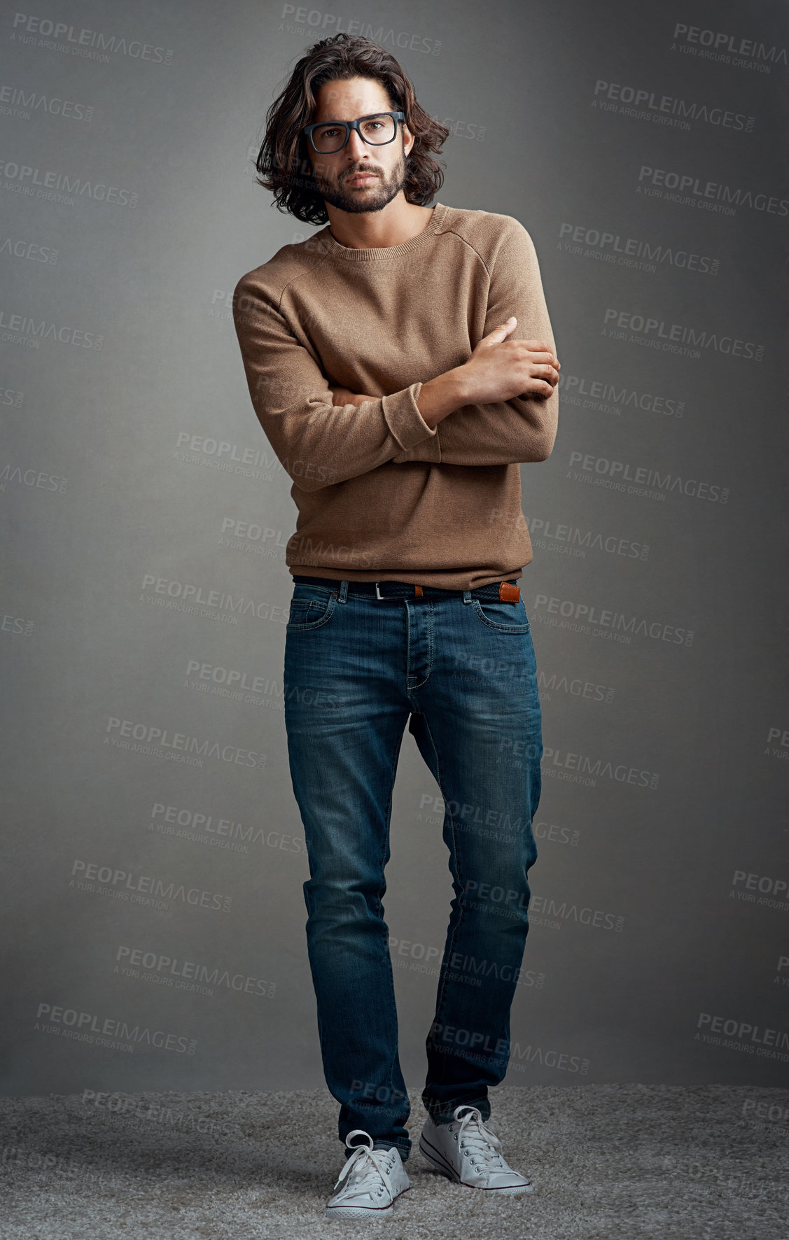 Buy stock photo Confident, man and fashion for portrait in studio for elegant, style and comfortable winter jeans clothes. Serious, male person and trendy jersey, designer glasses or hands crossed on grey background