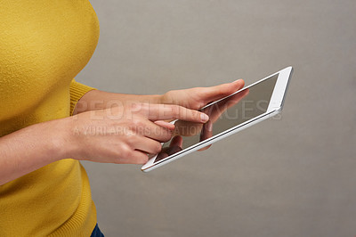 Buy stock photo Studio shot of an unrecognizable woman posing with her tablet against a grey background