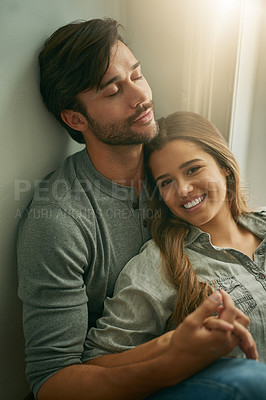 Buy stock photo Shot of an affectionate young couple at home holding hands and relaxing