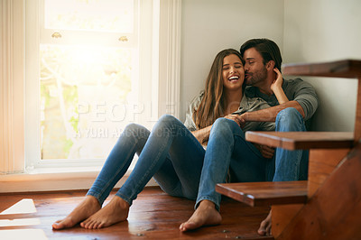 Buy stock photo Shot of an affectionate young couple sitting in a corner and holding each other