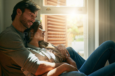 Buy stock photo Shot of an affectionate young couple holding each other at home in the sunlight
