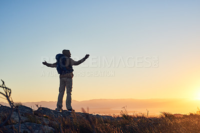 Buy stock photo Shot of a hiker on top of a mountain with his arms raised in the early morning