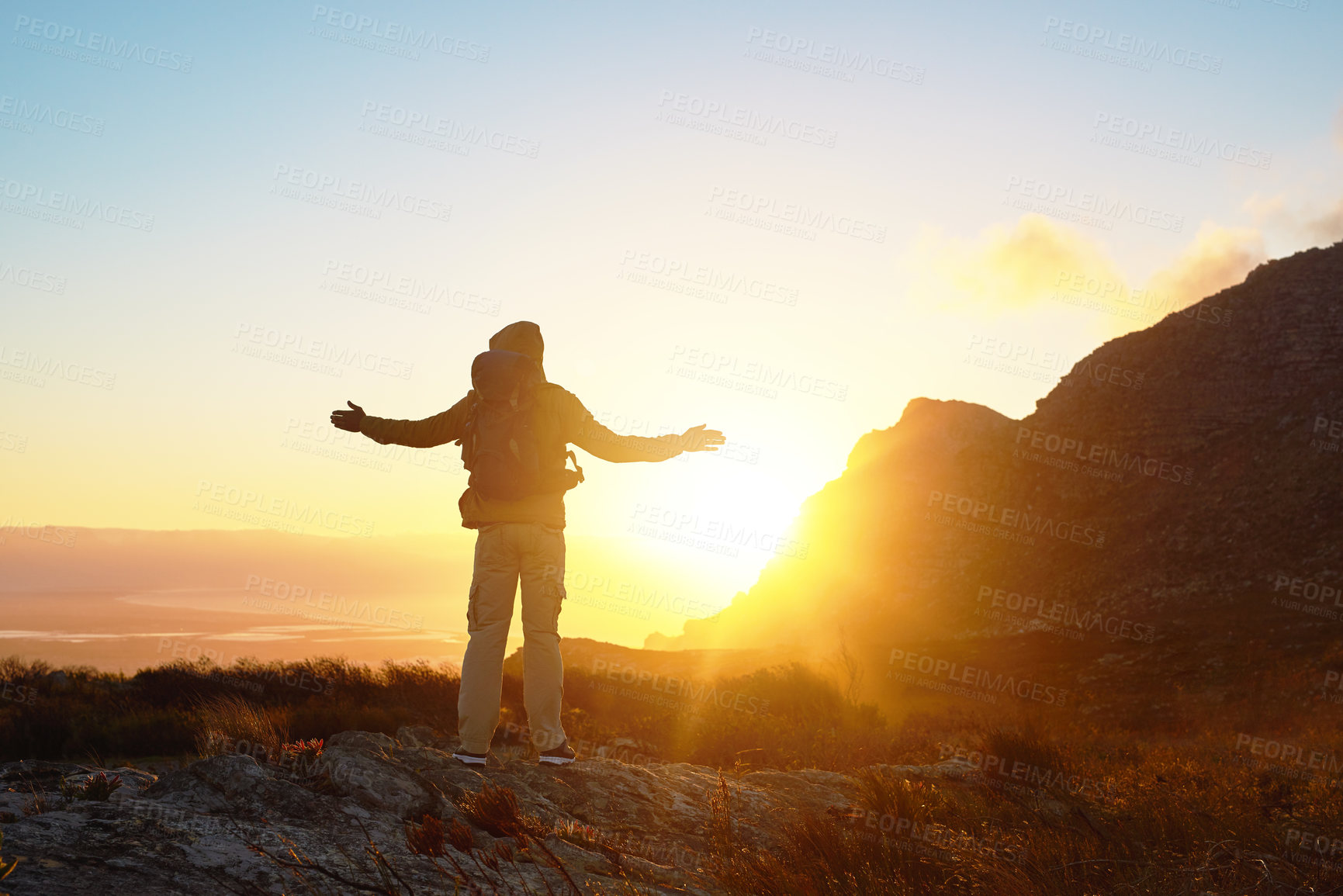 Buy stock photo Mountain, sunset and person with hiking success, achievement and freedom on trekking vacation. Sky, view and hiker with arms raised on cliff for outdoor adventure holiday in nature with backpack.