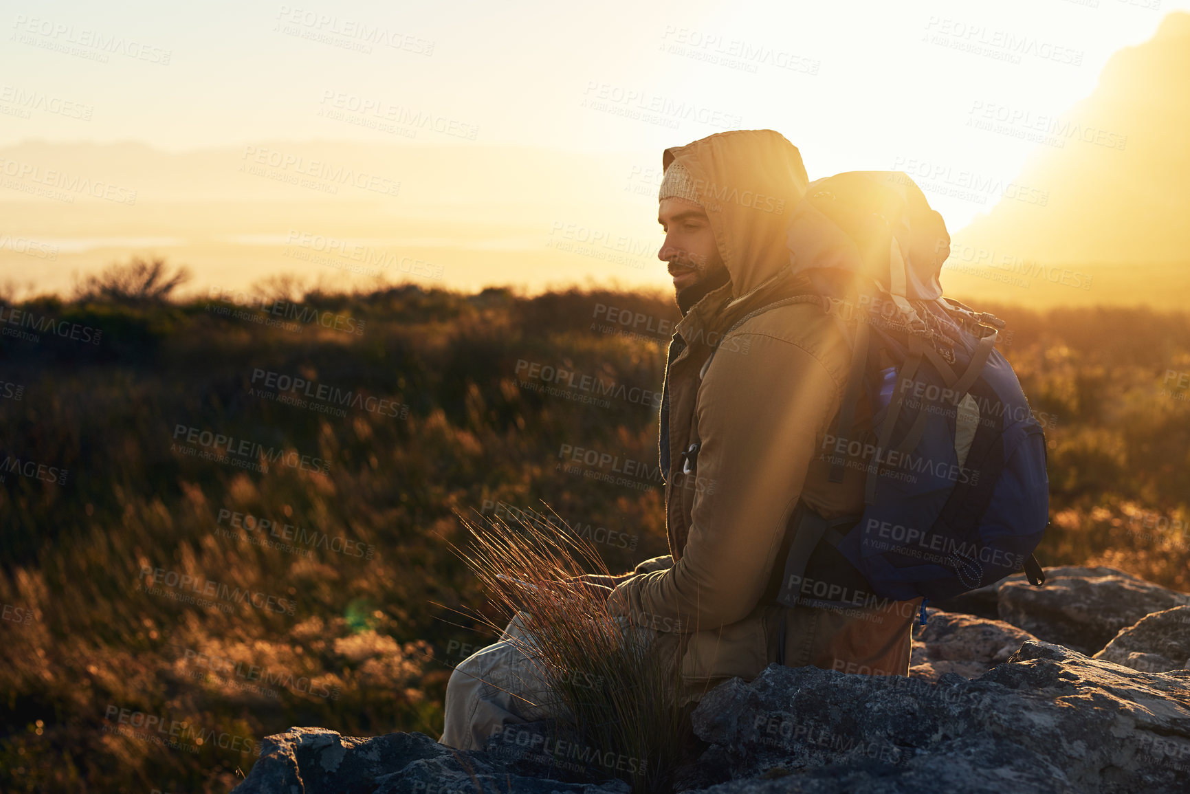 Buy stock photo Shot of a hiker siting on top of a mountain in deep thought