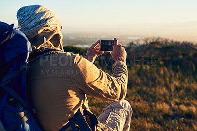 Buy stock photo Shot of a hiker on top of a mountain taking photos with his cellphone