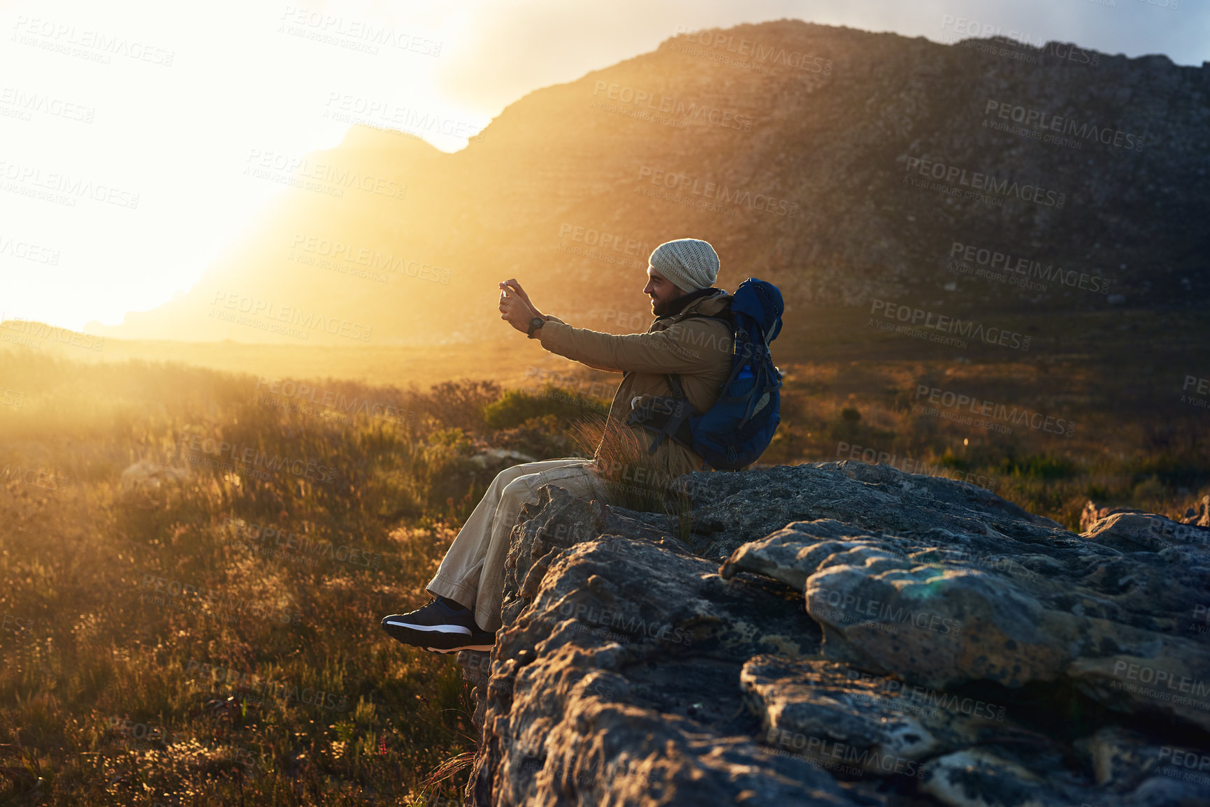 Buy stock photo Hiking, photograph and sunset with man in mountains for break, memory or scenic view of nature. Earth, flare and phone camera at sunset with happy person outdoor for adventure, fresh air or journey