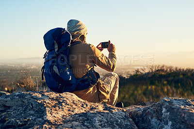 Buy stock photo Shot of a hiker on top of a mountain taking a photo with his cellphone