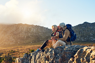 Buy stock photo Shot of two hikers sitting on top of a mountain having a conversation