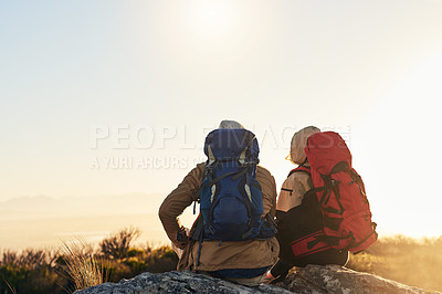 Buy stock photo Shot of two hikers sitting on top of a mountain looking at the view