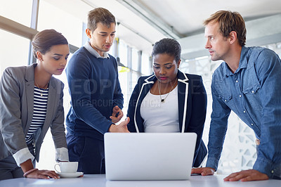 Buy stock photo Shot of a group of coworkers working together on a laptop in an office