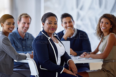 Buy stock photo Portrait of a group of smiling colleagues sitting together at a table in an office