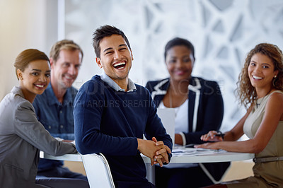 Buy stock photo Portrait of a group of smiling colleagues sitting together at a table in an office