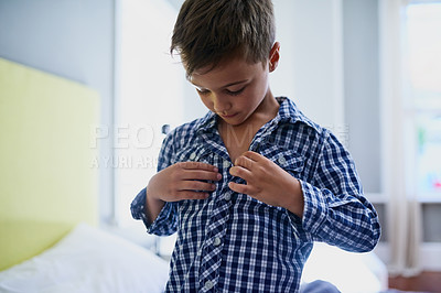 Buy stock photo Cropped shot of a young boy getting dressed in his bedroom in the morning