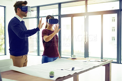 Buy stock photo Shot of two businesspeople wearing VR headsets while working together in an office