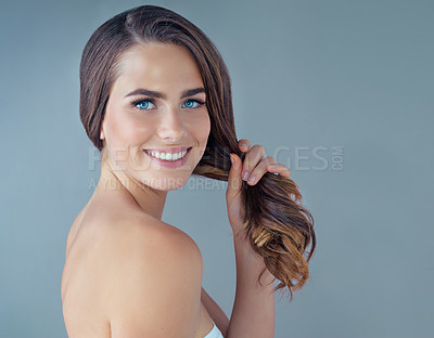 Buy stock photo Cropped portrait of a beautiful young woman posing against a grey background in the studio