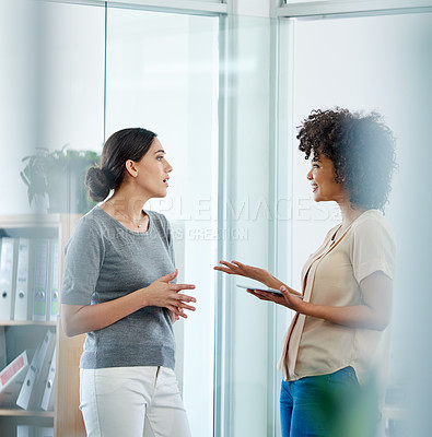 Buy stock photo Shot of two female colleagues having a discussion in their office
