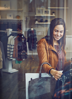 Buy stock photo Shot of a young woman shopping at a clothing store