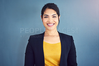 Buy stock photo Studio portrait of an attractive young businesswoman standing against a blue background