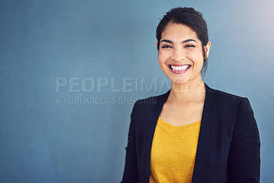 Buy stock photo Studio portrait of an attractive young businesswoman standing against a blue background