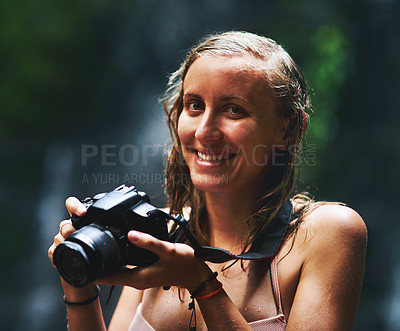 Buy stock photo Shot of a smiling young woman holding up a camera and looking happy as can be