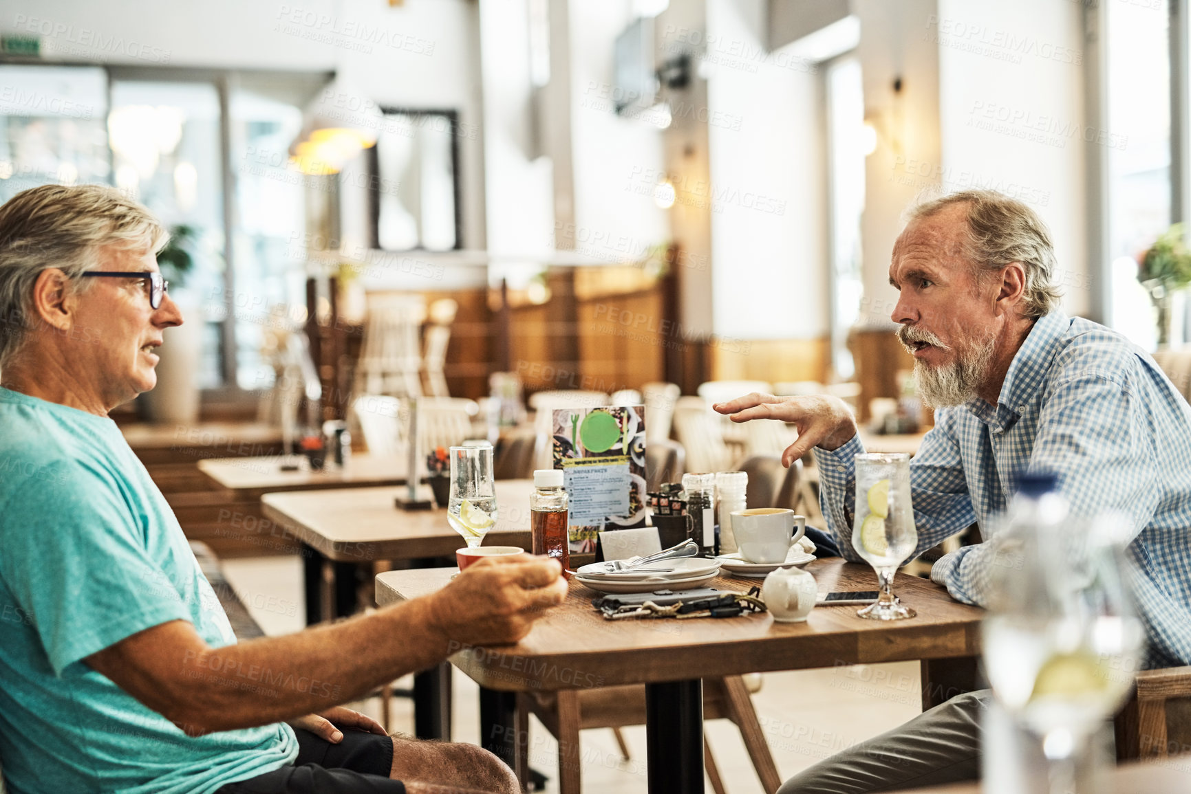 Buy stock photo Shot of two senior friends chatting at a table at their favorite cafe