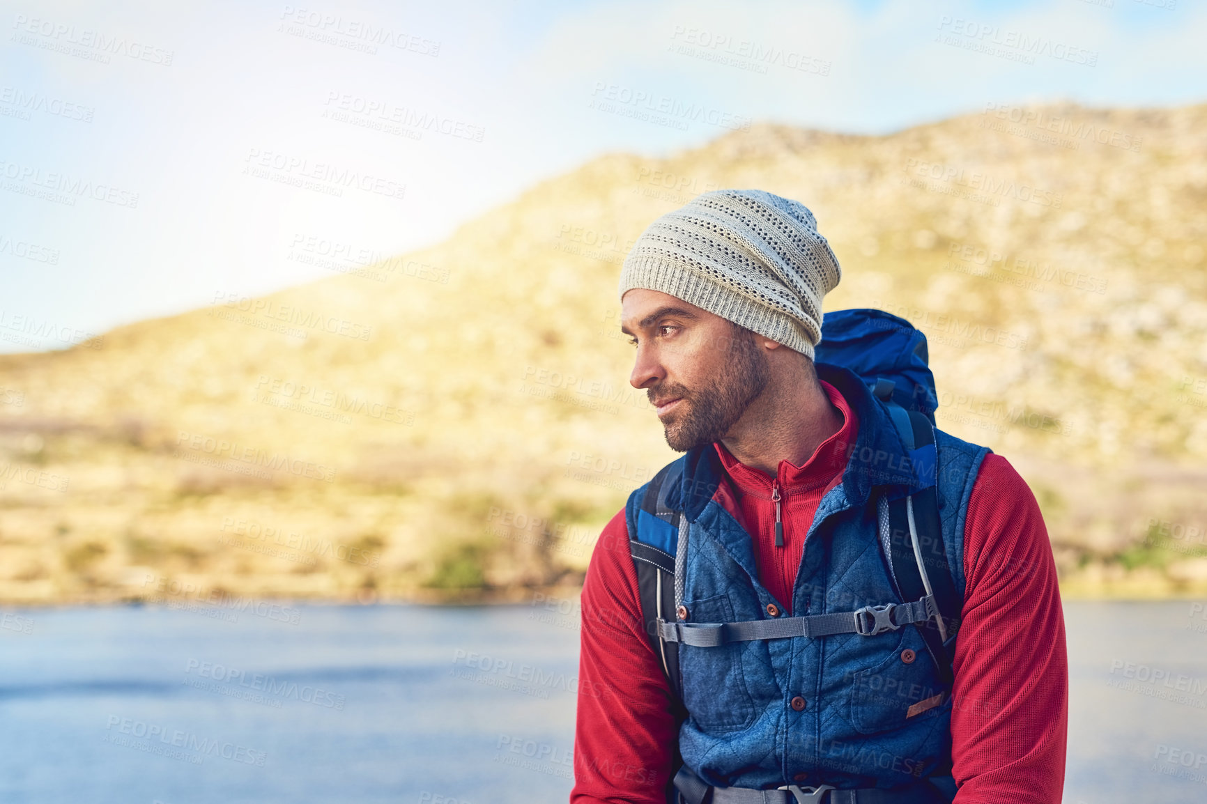 Buy stock photo Shot of a thoughtful hiker admiring the view of a lake on a sunny day