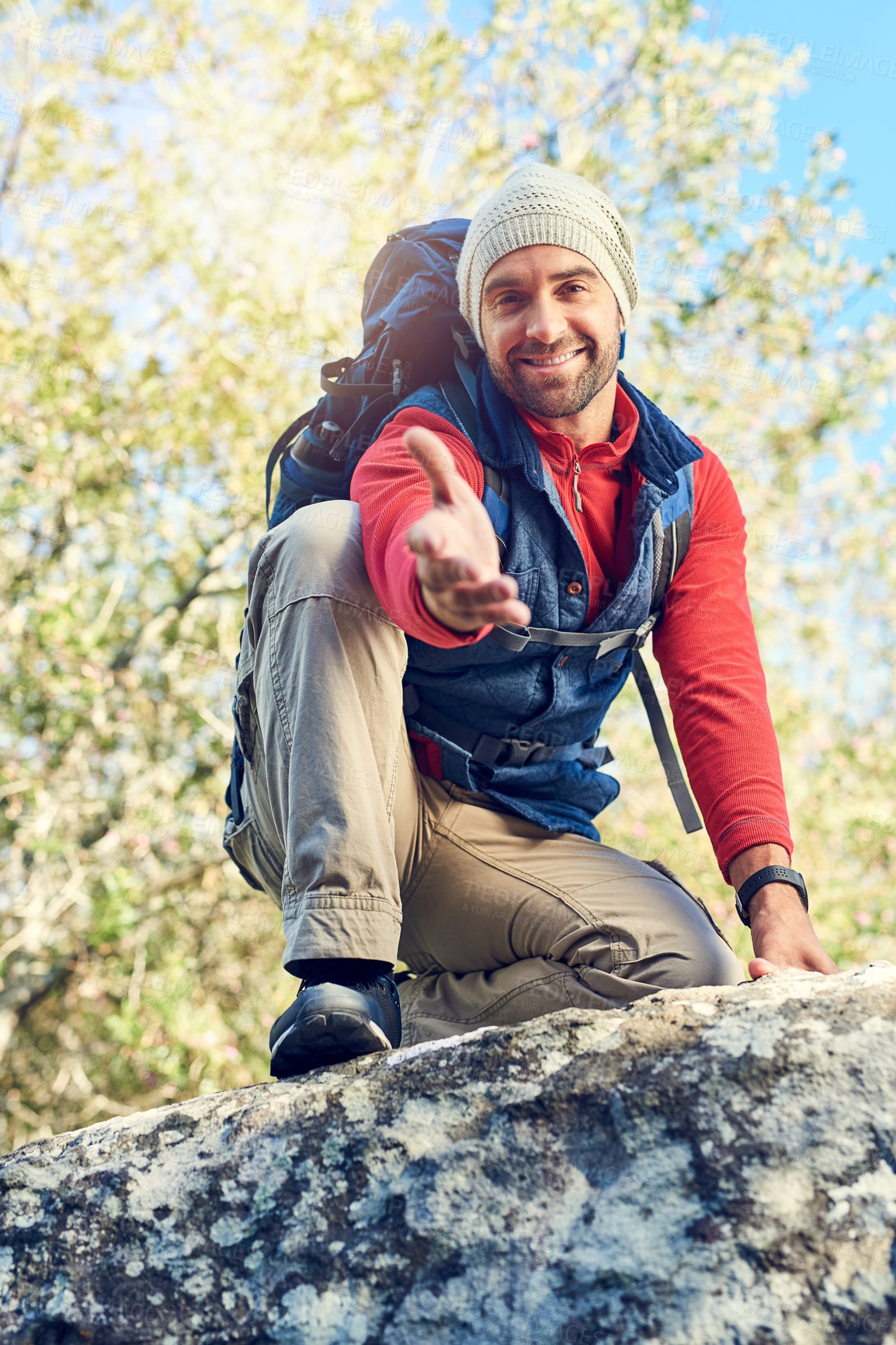 Buy stock photo Portrait of a happy hiker extending his hand while sitting on top of a rock on the trail