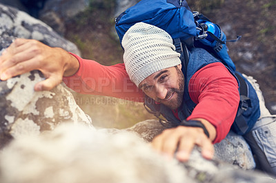 Buy stock photo Shot of a happy hiker climbing over rocks on a mountain trail