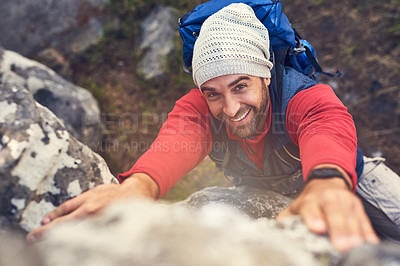 Buy stock photo Shot of a happy hiker climbing over rocks on a mountain trail
