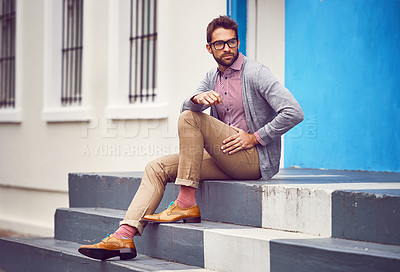 Buy stock photo Shot of a handsome young man seated on steps outside in the city while being in deep thought