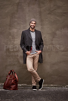 Buy stock photo Fashion, wall and portrait of male person, autumn and trendy clothing for cool weather. Bag, coat and travel for vacation with contemporary and stylish man tourist, edgy and happy in city urban area