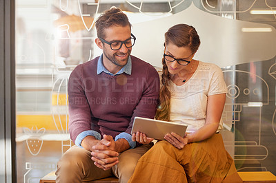 Buy stock photo Shot of two happy young business owners using a tablet together while sitting outside their coffee shop
