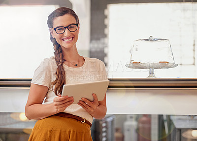 Buy stock photo Portrait of happy young business owner using a tablet while standing in her coffee shop