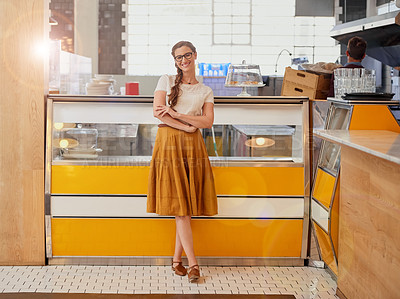 Buy stock photo Portrait of a happy young business owner posing in front of the counter in her coffee shop