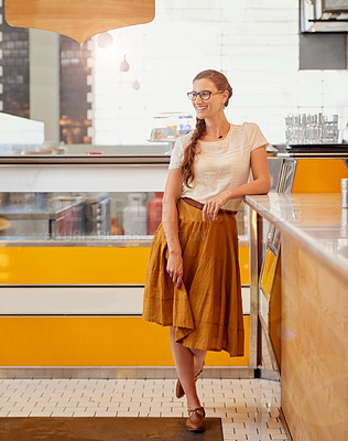 Buy stock photo Shot of a happy young business owner posing in front of the counter in her coffee shop