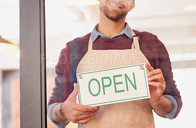 Buy stock photo Portrait of a young business owner standing in the doorway of his coffee shop with an open sign