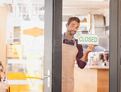 Buy stock photo Portrait of a young business owner putting a closed sign in the window of his coffee shop